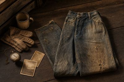 Vieux jean vintage usé sur bois ancien avec montre à gousset et photos sépia — ambiance patrimoine